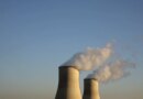 Cooling towers for a nuclear reactor stand against a blue sky.