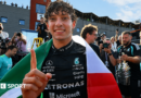 Kimi Antonelli celebrates after winning the Belgium Grand Prix, with an Italian flag draped over his shoulders 