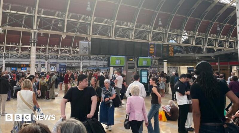 Crowds fill the concourse of London Paddington station with the departure boards blank showing no services.