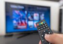 A remote being held in front of a Smart TV.