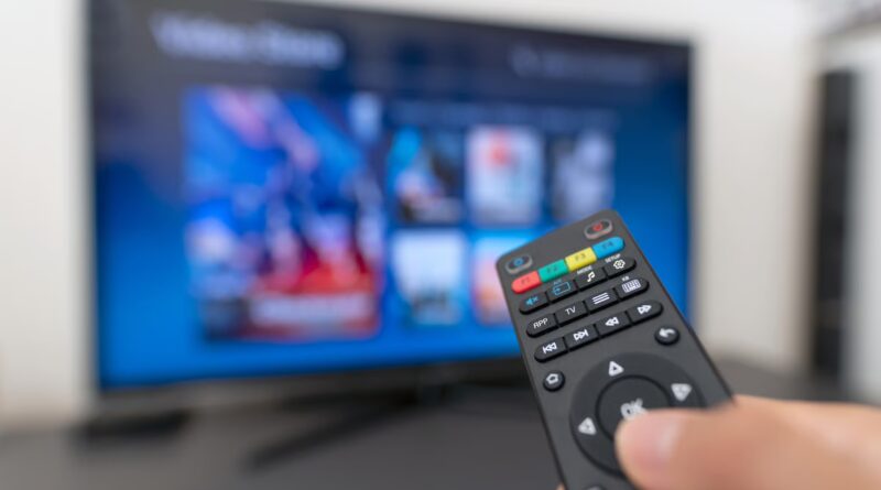A remote being held in front of a Smart TV.