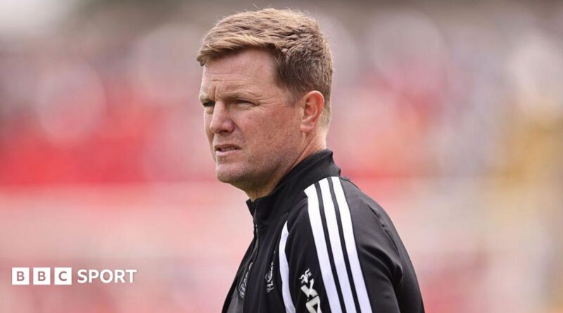 Eddie Howe, wearing a black-and-white tracksuit stop, looks on before a Newcastle match