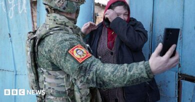 Local resident watches a video message of her relative on the smartphone of a Chechen Akhmat battalion fighter in the village of Kazachya Loknya in March 2025