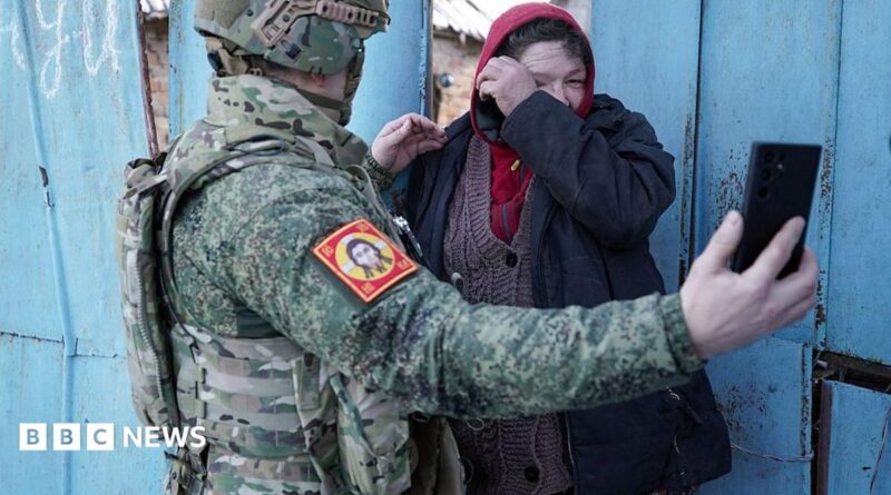 Local resident watches a video message of her relative on the smartphone of a Chechen Akhmat battalion fighter in the village of Kazachya Loknya in March 2025