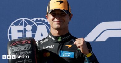 Lando Norris clenches his left fist in celebration while holding the pole position award at the Spanish Grand Prix
