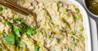 Close-up of creamy chicken pesto orzo with peas, sun-dried tomatoes, pesto, and fresh parsley.