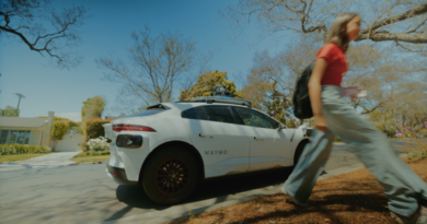 A Waymo robotaxi on the street in Phoenix and a teenage girl walking away from it.
