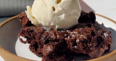Fudgy cottage cheese brownie topped with a scoop of vanilla ice cream on a ceramic plate.