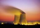 Nuclear power plant cooling towers emit steam at dusk.
