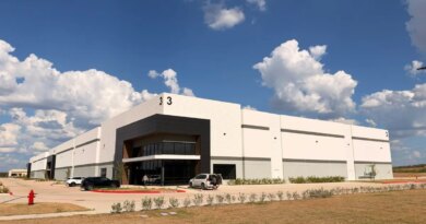 A white warehouse stands against a partly cloudy sky.
