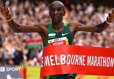 Eliud Kipchoge holding his arms aloft as he wins crosses the finish line.