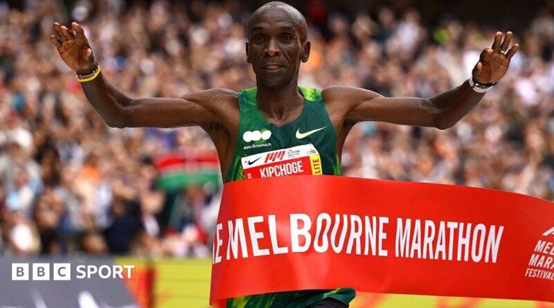 Eliud Kipchoge holding his arms aloft as he wins crosses the finish line.