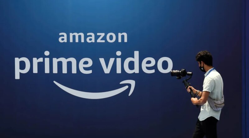 A cameraman records a video near the poster of Amazon Prime Video launch in Mumbai.