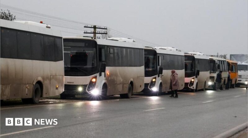 A row of white coaches are parked up on the side of the road