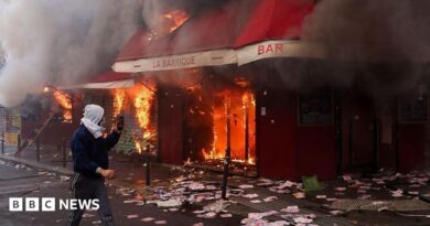 A man films as smoke rises from the bar 'La Barrique' on the sidelines of a demonstration against the "high cost of living", in Paris.