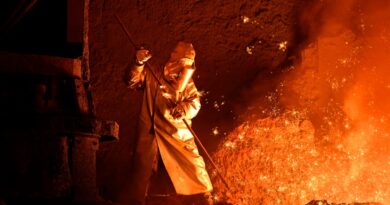 A steelworker takes a sample from a blast furnace.