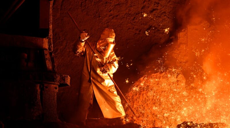 A steelworker takes a sample from a blast furnace.
